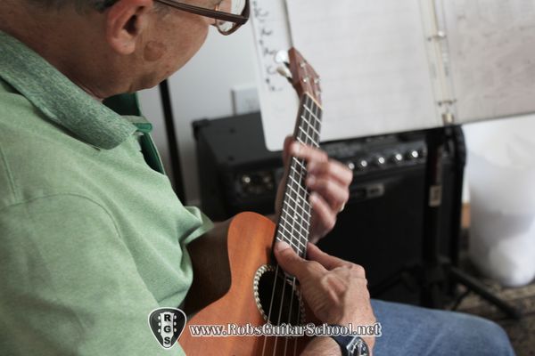 Adult playing ukulele in Newton, Groton, MA