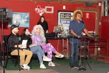 Monikkrome backing up comics at the 5th Annual Birthday Roast of Symply Courtney. Feb 8, 2024 at the Tiniest Bar in Texas in Austin, TX. Comics pictured from left to right: Dizzy, Grace Morton, Tiffany Epiphany, Jose Da'Hype (on the mic).
