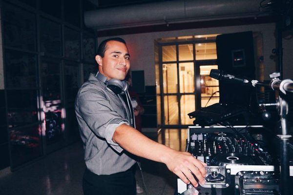Omar Blanco Valentin from Musical Genius Productions DJing a High School Dance with Headphones Around Neck and Turntables in Front 