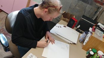 Baltimore artist Mitchell Noah hand-signing the art programs
