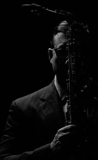 film noir image of man holding Buffet Crampon alto saxophone