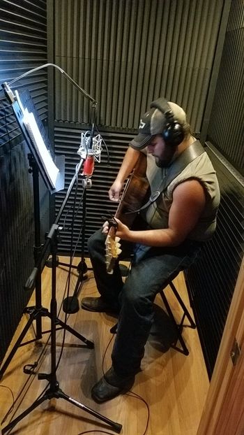 Austin Zackary recording an acoustic guitar track in the booth.
