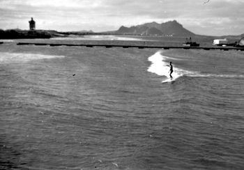 Brian Barnes surfing the 2nd peak (south peak).photo taken from the pier(north peak in the distance. you can clearly see how the sandhills had been carved out on the other side,and the most fantastic bowling left would peel down there!! sand movement also caused neat little peak to develop where Brians surfing! The black pipe on floats was the sand pump!
