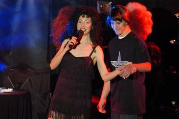 'One Voice" live show image - an audience member performs on stage ' I Got You Babe" as Sonny, wig and all supplied by Bethany as Cher, a real show stopper
