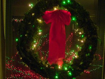 Wreath, with lit tree in background
