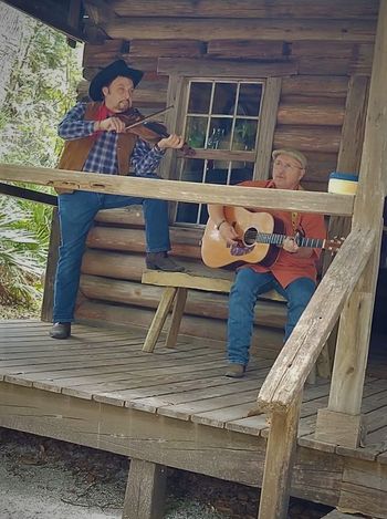 Playin on the porch of a log cabin and shooting a video.

