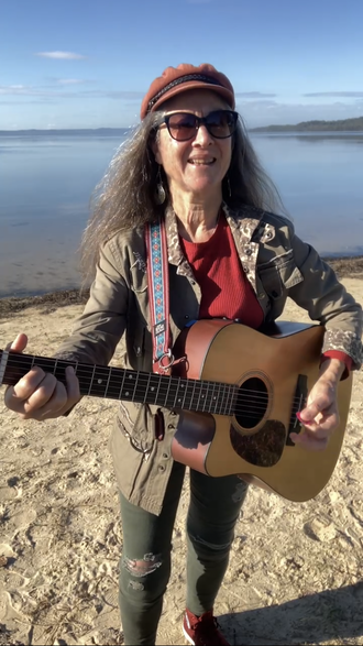Kristine Best with her Martin guitar at Canton Beach, New South Wales and she's wearing her trademark cap.Australia