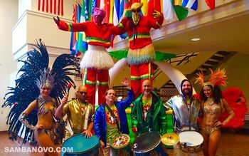 Samba drummers posing with samba dancers and moco jumbies all smiling after giving a performance at a corporate event
