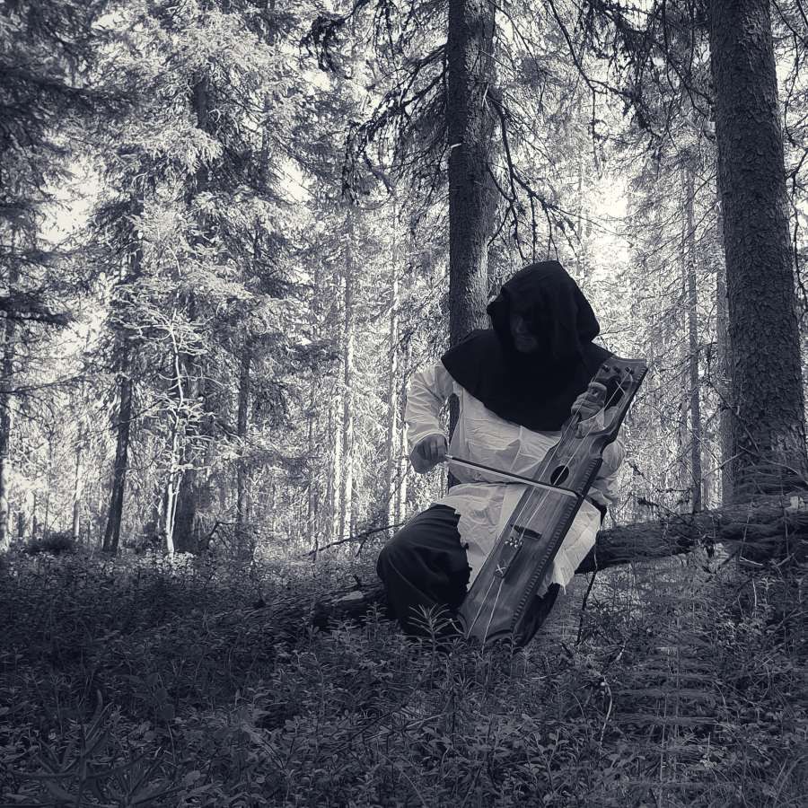 Musician wearing medieval costume with Talharpa performing in the woods in eastern Finland