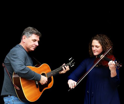 Martin Smit playing the guitar and Meghan Balogh on fiddle during a performance