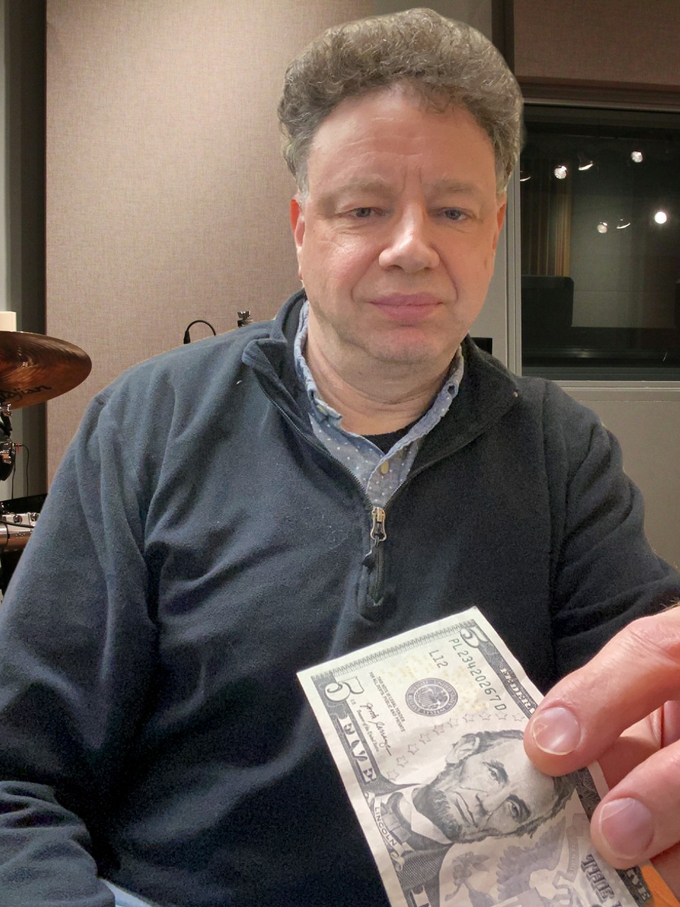 Jason Didner holding a five-dollar bill in a recording studio