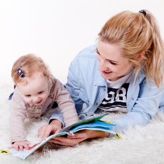 Mum on the floor with baby, enjoying reading a children’s book together.