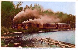 Scores of Edwardian scenes and thousands of post cards were printed
that depicted Ontario's tiny Huntsville & Lake of Bays Railway. At just over one mile in length, it was undoubtedly the most photographed railway on a 'picture per mile'basis. This view is an example of a highly manipulated image, where a box car and three passenger cars are seen
negotiating the curve by Osborne's Lake. But wait - the line only had two
operational passenger cars at any one time! The third has been manually
added, debunking the saying that a photograph never lies. The H&LOB was much visited by railfan photographers in the post-World War II years, right up to its abandonment in 1959. The era between
the wars is well documented in the albums of local cottagers and full-time residents, and the earlier Edwardian post card views
complete the line's historical record. Jeffery Young, the owner of this fairly common card and friend Peter Foley are researching a detailed and updated illustrated history of the H&LOB.