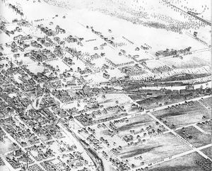 A "Bird's Eye View" of Lindsay map, 1875, showing the route of the Port Hope, Lindsay & Beaverton Railway through Lindsay along the east bank of the Scugog River, crossing to the west bank by means of the swing-bridge in the centre-right of the view, and then making its way out to Beaverton in 1861.