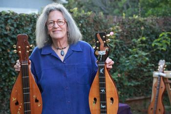 Joellen holding the Crying Seahorse Dulcimer and the Pelican Dulcimer with the Ram on the far right.