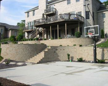 1st phase - upper wall and patio under deck 2 nd phase lower patio and fire pit and stair case to basket ball court note: to my left is a play ground area supported by another retaining wall Elevation changes are our specialty