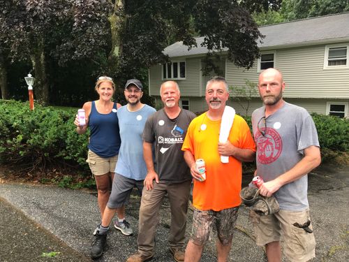 A group of fans volunteering to help a community member with yard work