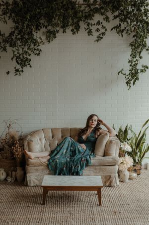 Americana musician Sarah King lounging on a cream sofa in a green dress