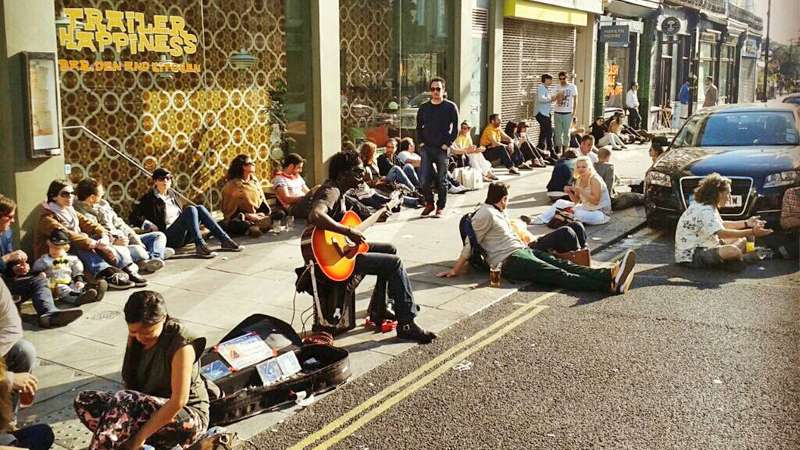 I See Hearts - Ryan Koriya busking on Portobello Road in Notting Hill London with fans sitting on the pavement and sunny road