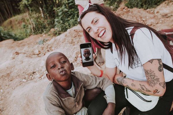 Charlotte Archer in Uganda with a little boy and her cell phone - Photo by Charlotte Robinson