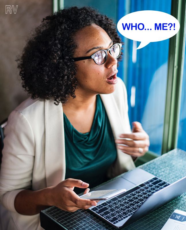Surprised woman with spectacles on laptop and smart phone with curly hair