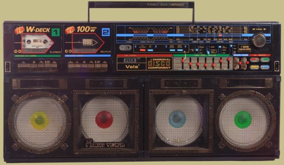 A disco boombox, photographed in the daytime, where four bulbs are shown in the centre of the speakers. It is bulky and has 80s styling.
