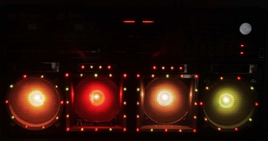 Four glowing, bright colour bulbs, which continue from the picture above, with smaller, multicoloured lights dotted around. This is the boombox photographed in darkness, looking almost festive.
