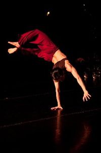 Upside Down dancer wearing red pants and a brown shirt