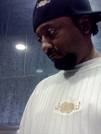 J.O.T. aka GRANDE GATO WEARING WHITE SOUL-FULL WEAR SHIRT WITH METALLIC GOLD LOGO STANDING IN FRONT OF FUTURISTIC BACKGROUND(2012)