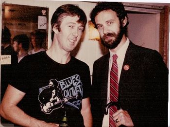 Yes, you are correct. That is British R&B figurehead Spencer Davis in a Blues Outlet T-shirt and Bob Angell dressed as an English gent complete with umbrella. Curiouser and curiouser, eh? (1985)