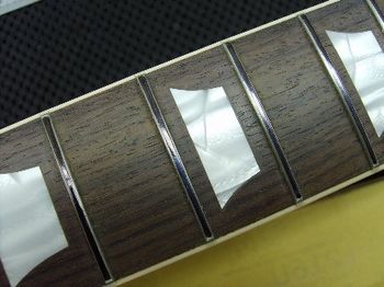 The inlays have been leveled, and the fretboard and inlays have been polished back to a beautiful luster. The black marker on the frets indicates that they are about to receive a leveling and dress.
