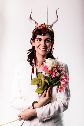 Medusa, trans nonbinary alt-pop musician and rapper; white suit, tuxedo, tiara, horns; bouquet of flowers; fake blood; prom scene, Carrie; photographer Justin Ruggiero