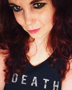 Jezebel Jones - woman with long red hair, pale skin, wearing a tank top that says 