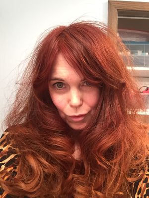 Jezebel Jones - woman with long red hair, pale, freckled skin, blue-green-hazel eyes in a fitted leopard print dress.