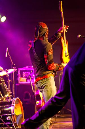 Guy rocking on stage in multi-colored jackets with long hood