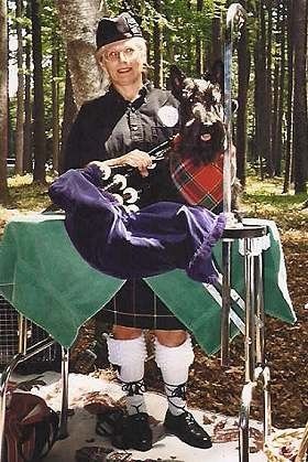 Requested to represent his breed at the annual Scottish Highland Festival in Northampton, MA, Jasper flirts with a pretty Bagpiper player! Jasper is wearing the official tartan of the Drummond clan.
