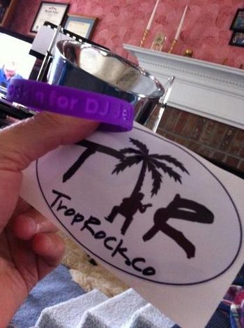 Trocker Bry Harris wraps his purple bracelet around Linda's steel drum w/his TropRock.co sticker
