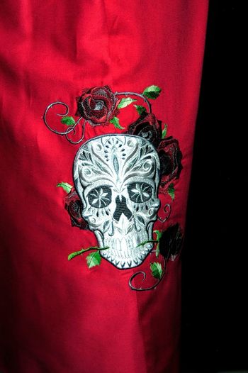 Sugar skull is emboidered on the side of the red skirt after the seam was sewn first.
