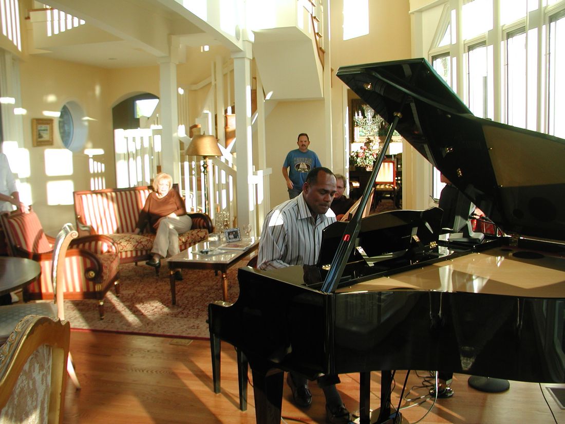 McKinley at the piano. His mother is seated behind him on the couch.
