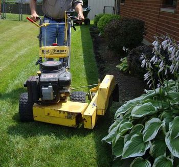 Disc-style bedshaper cutting straight-line mulch bed edge.
