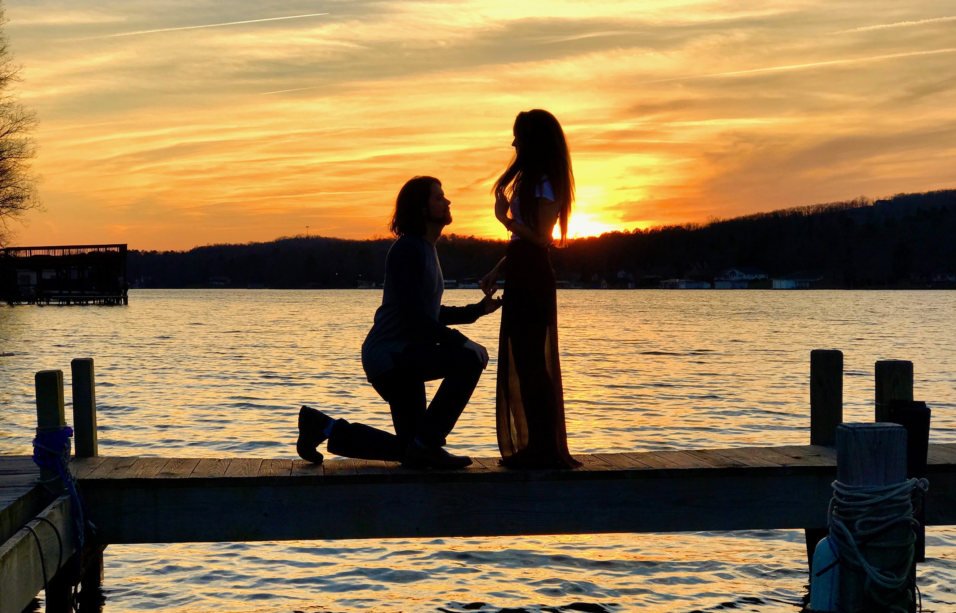 guy on one knee proposing on boat dock on the lake