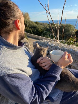Cat cuddling Giuseppe while he drinks tea