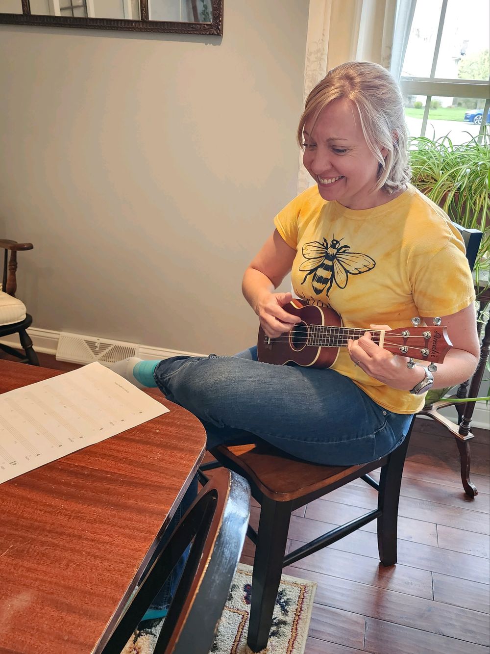 Songdog Music student playing ukulele with sheet music smiling