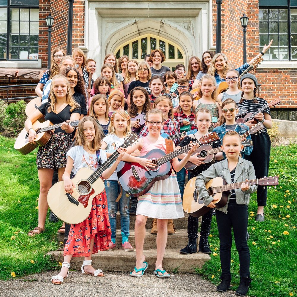 Group of young females holding acoustic guitars