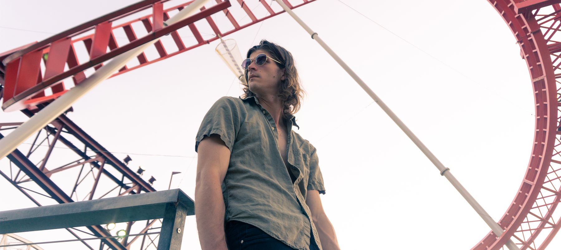 Jon Worthy, dressed in a short sleeved shirt and wearing sunglasses, standing in front of a red frame structure.