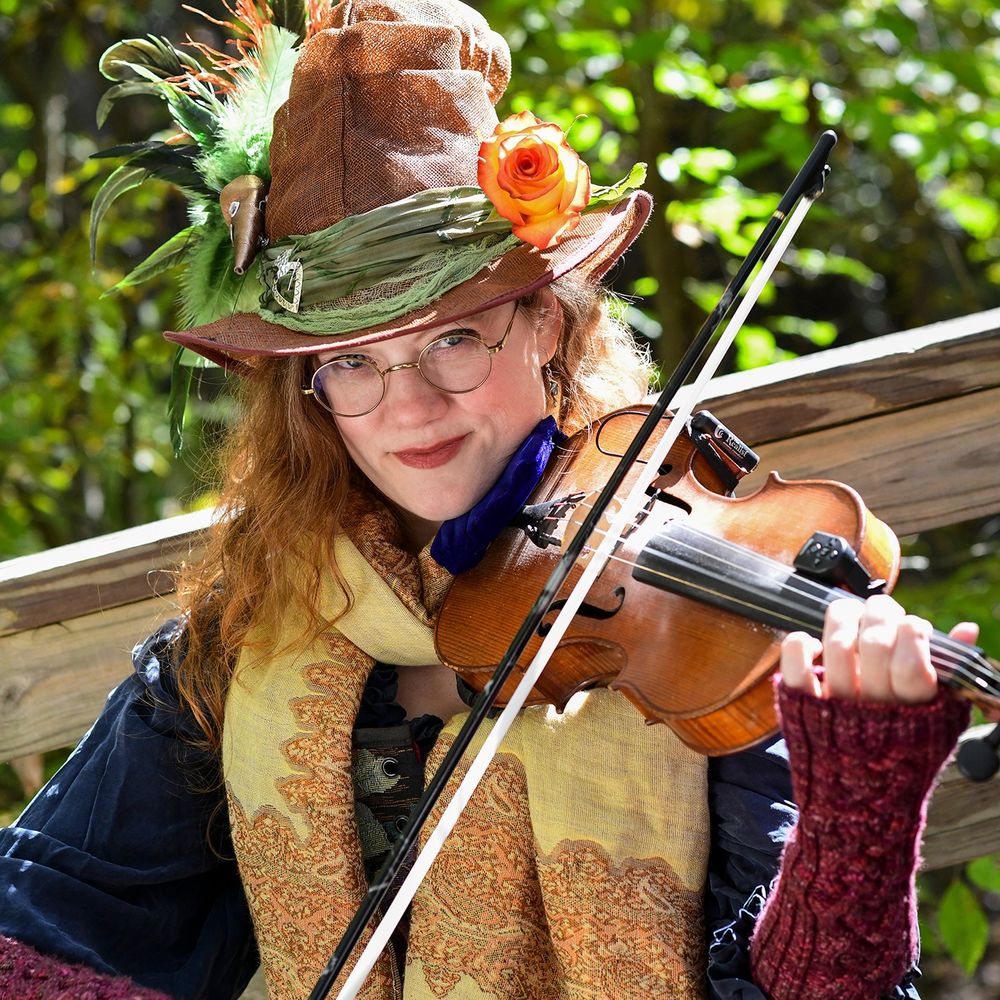Donna wearing a flower crown, playing a fiddle