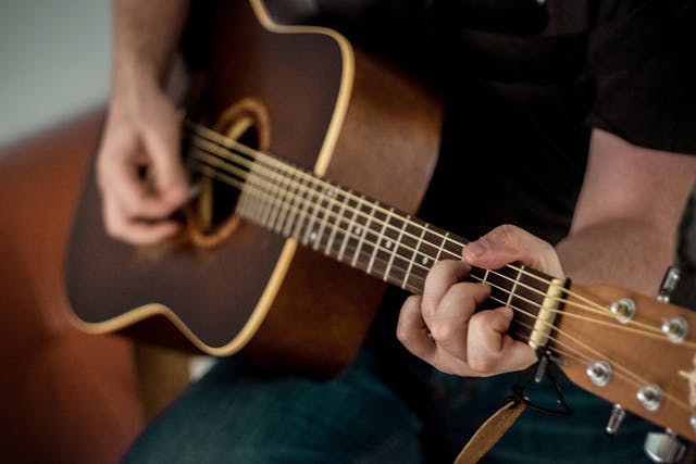 Acoustic guitar held by musician playing
