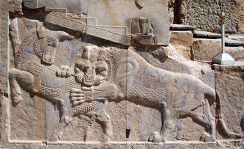 Frieze from Persepolis showing a lion attacking a beast with one visible horn.
