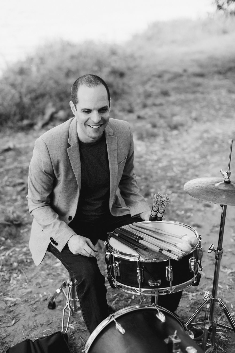 Dor Herskovits sitting at the drum set smiling with a variety of sticks 