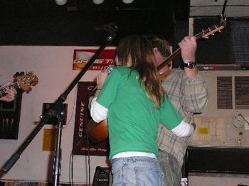 Jules hugs Johnny as he plays guitar.
